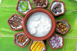 Overhead view of Ice Biryani ingredients arranged in terracotta bowls on green banana leaf with curd, green chilies, onions, and spices