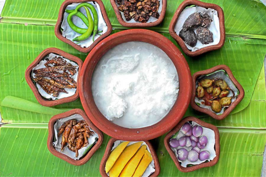 Overhead view of Ice Biryani ingredients arranged in terracotta bowls on green banana leaf with curd, green chilies, onions, and spices