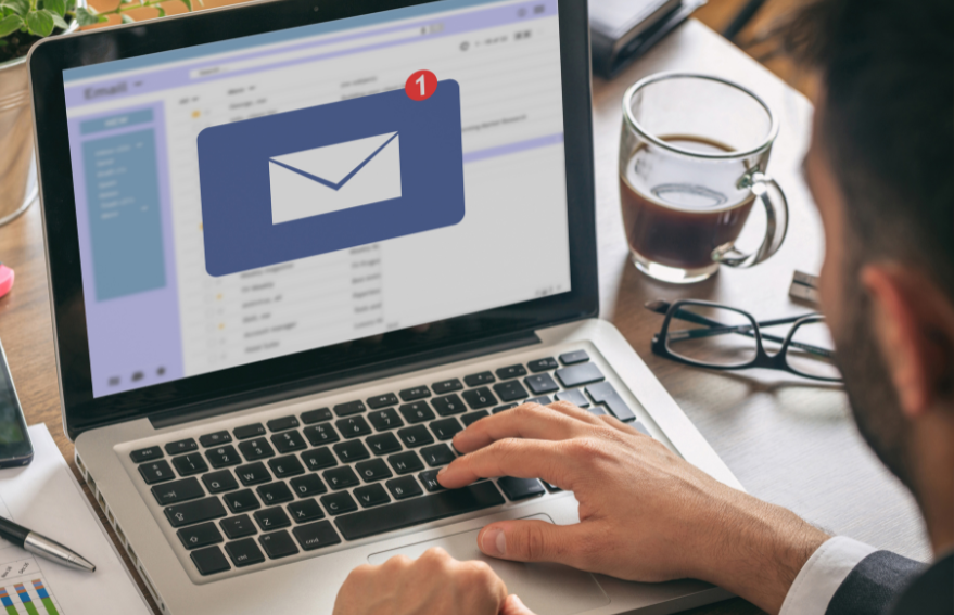Professional at desk receiving email notification on laptop with red alert badge