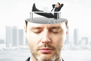 Relaxed businessman lying on laptop atop an open human head, symbolizing stress-free mindset and calm thinking above a city skyline.