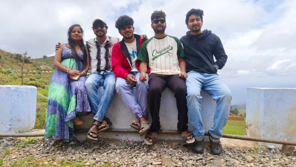 Five-member marketing team sitting together at a hilltop viewpoint during an Ooty workcation